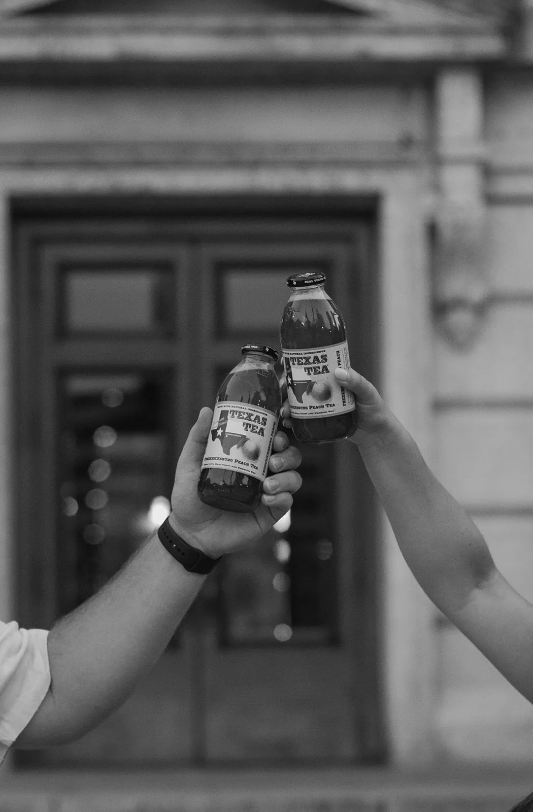 Black-and-white close-up of two bottles clinking