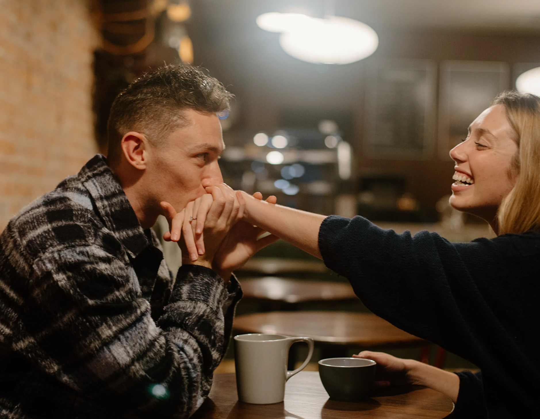 Gerrin kissing Meredith's hand across a café table as she laughs