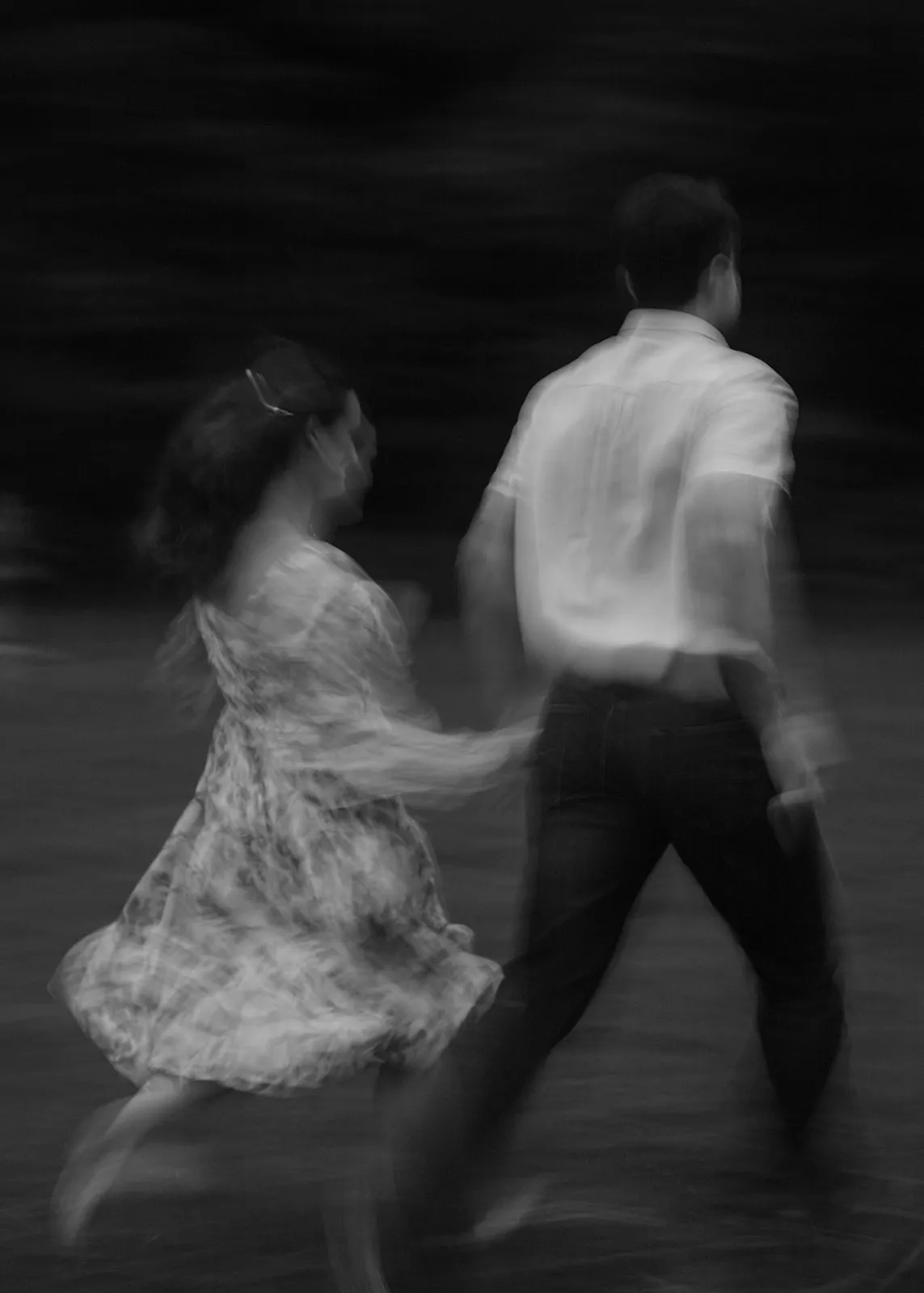 Black-and-white motion blur of John and Grace running hand in hand