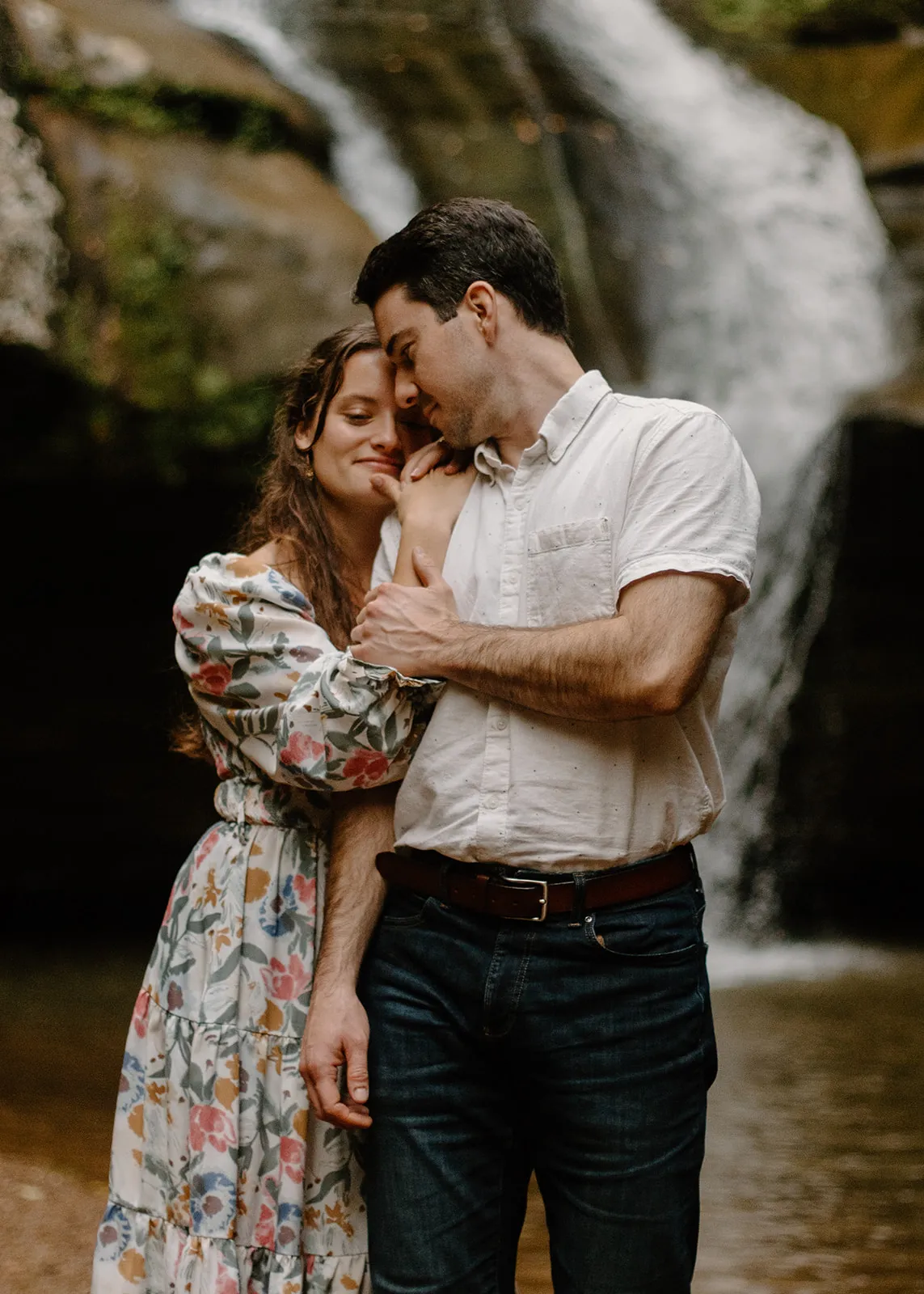 John and Grace embracing in front of a waterfall