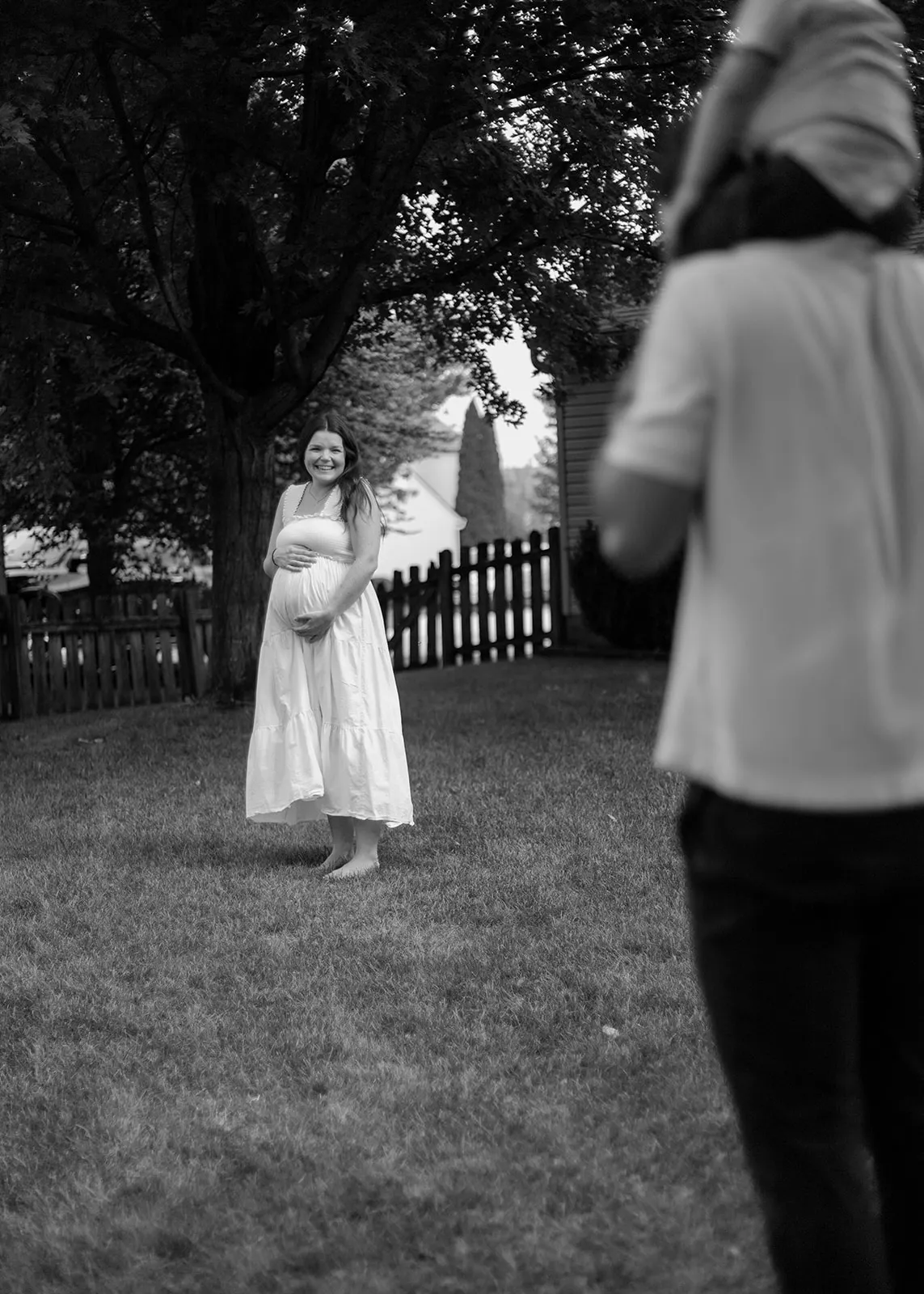 Black-and-white of mom cradling her belly across the yard