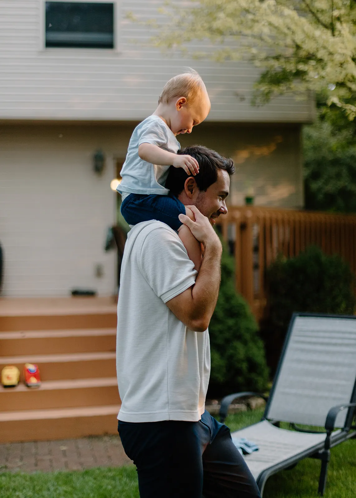 Their son riding on dad's shoulders by the back steps